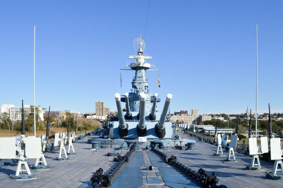 View from the bow with 6, 16 inch guns pointed overhead and the waterfront of Wilmington in the background.